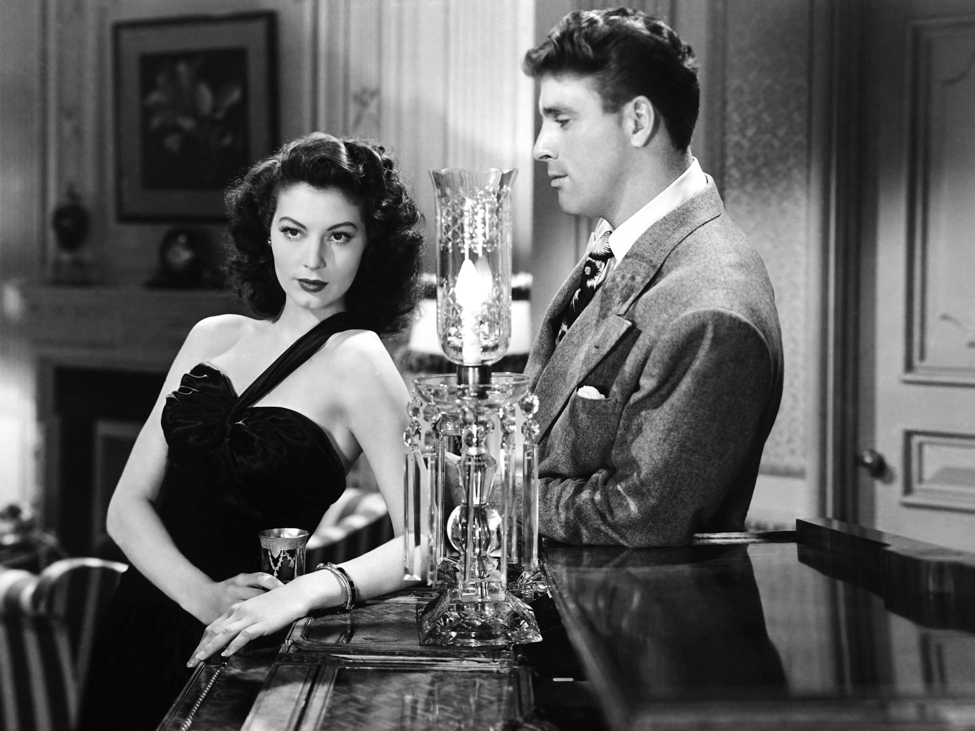 Ava Gardner und Burt Lancaster stehen an einem Klavier. Zwischen ihnen steht eine Lampe.