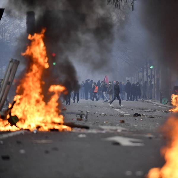 Protestierende stehen hinter Flammen.