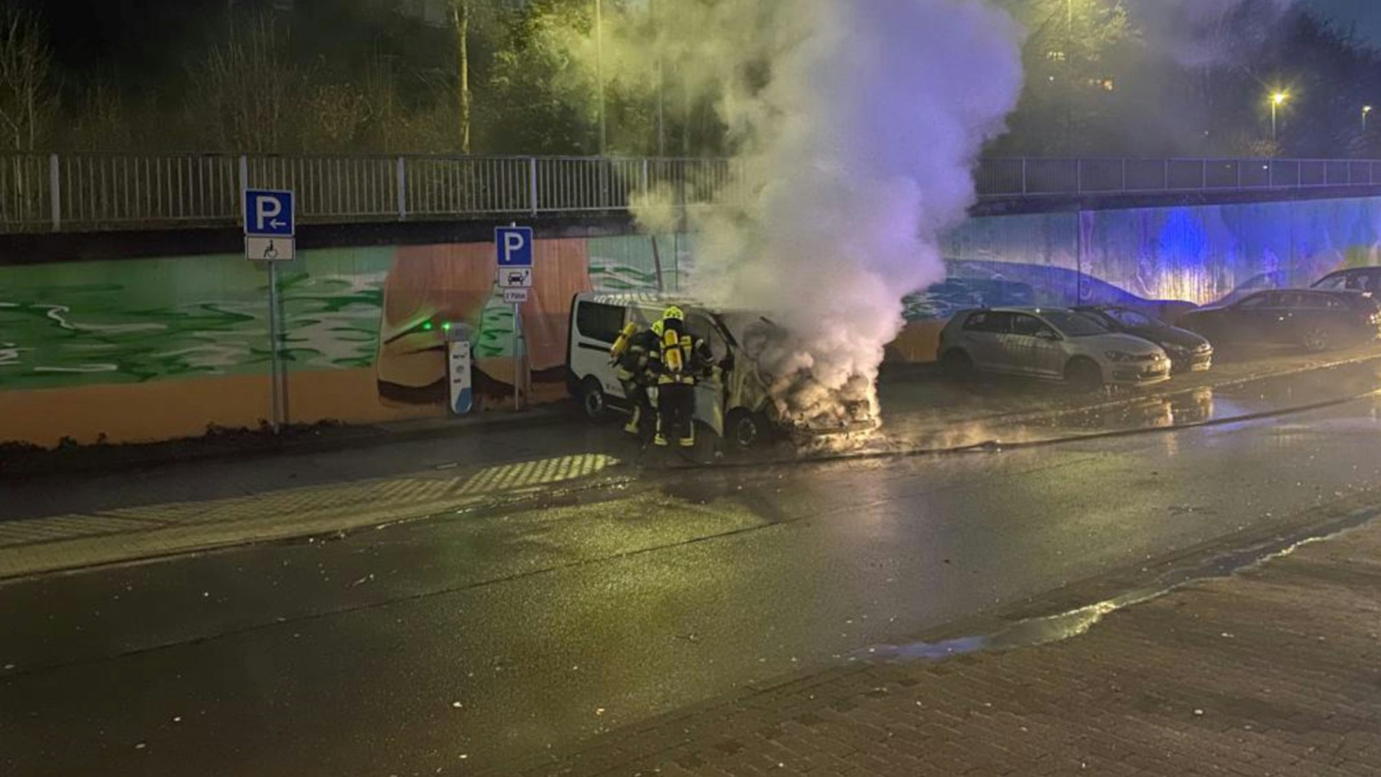 Ein brennendes Auto in Wipperfürth, Feuerwehrleute löschen das Fahrzeug.