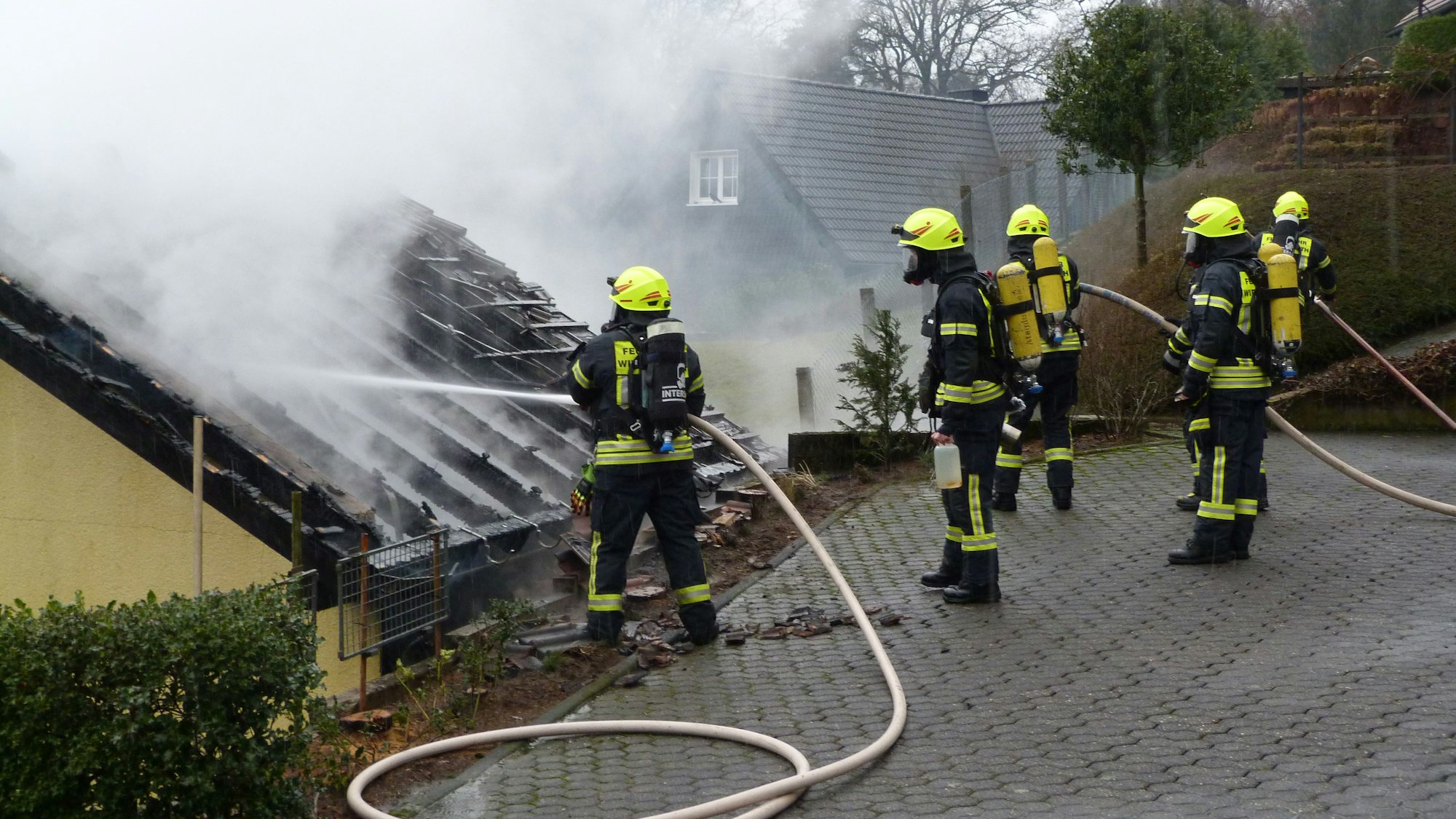 Feuerwehrleute löschen einen Brand an einem Carport.