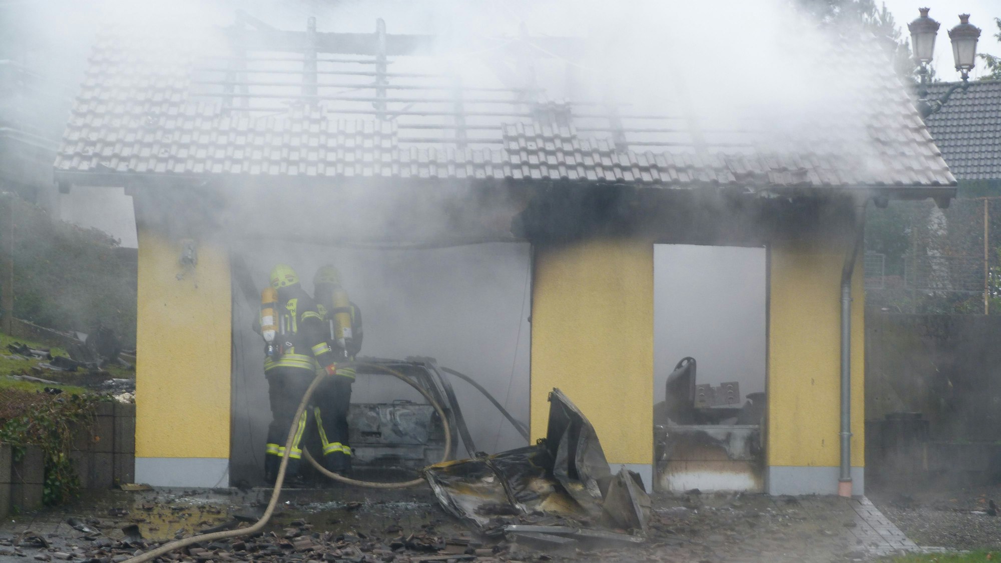 Feuerwehrleute löschen einen Brand an einem Carport.
