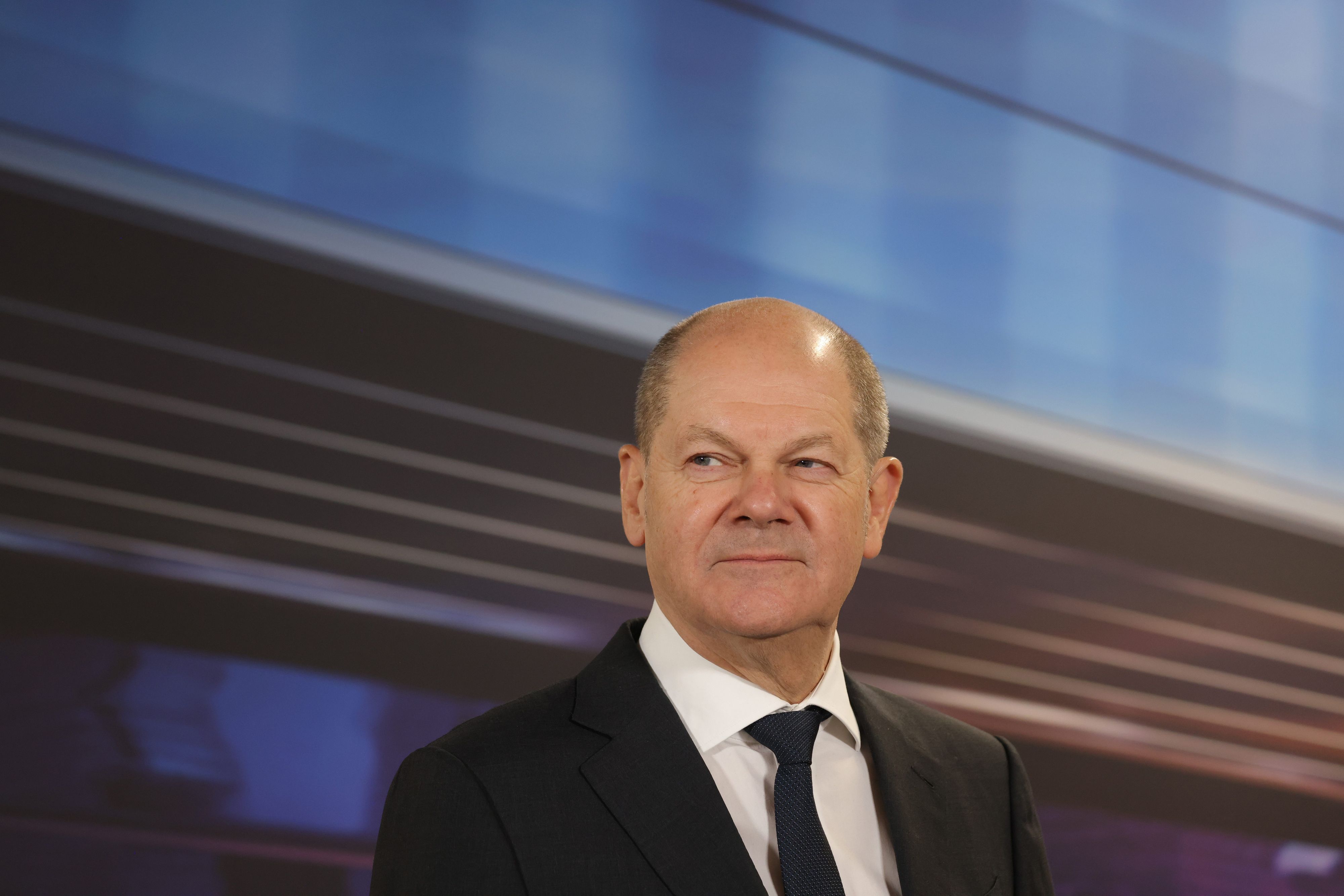 Bundeskanzler Olaf Scholz steht im Anzug in einem BMW-Werk.