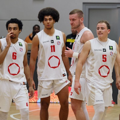 Fünf Basketballspieler befinden sich auf dem Weg aufs Spielfeld.