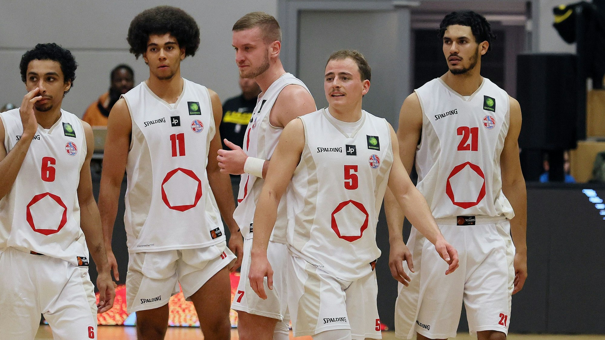 Fünf Basketballspieler befinden sich auf dem Weg aufs Spielfeld.