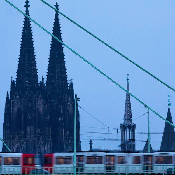 Eine Straßenbahn fährt am frühen Morgen vor der Kulisse des Doms über die Severinsbrücke.