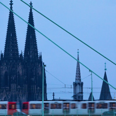 Eine Straßenbahn fährt am frühen Morgen vor der Kulisse des Doms über die Severinsbrücke.