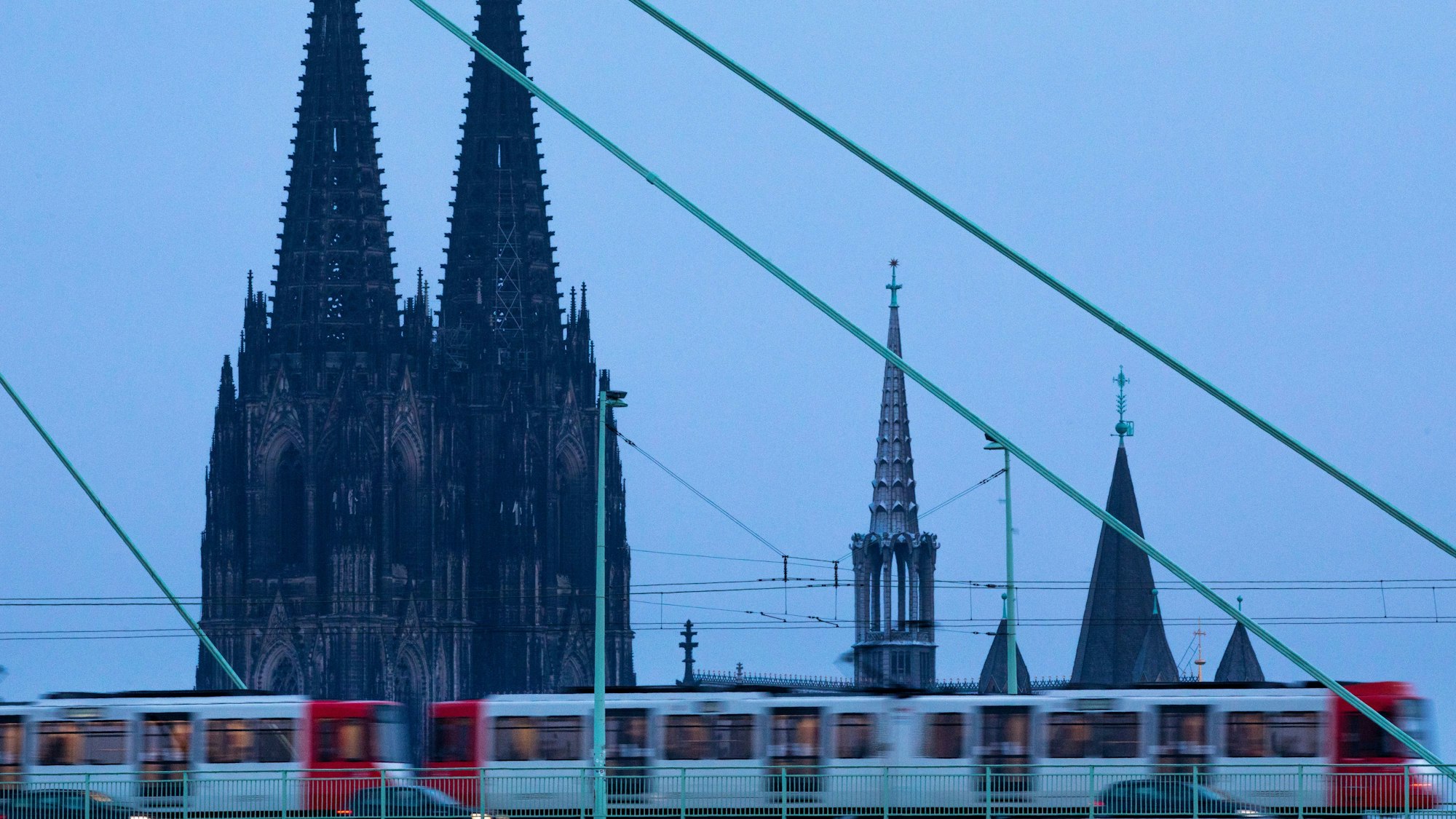 Eine Straßenbahn fährt am frühen Morgen vor der Kulisse des Doms über die Severinsbrücke.