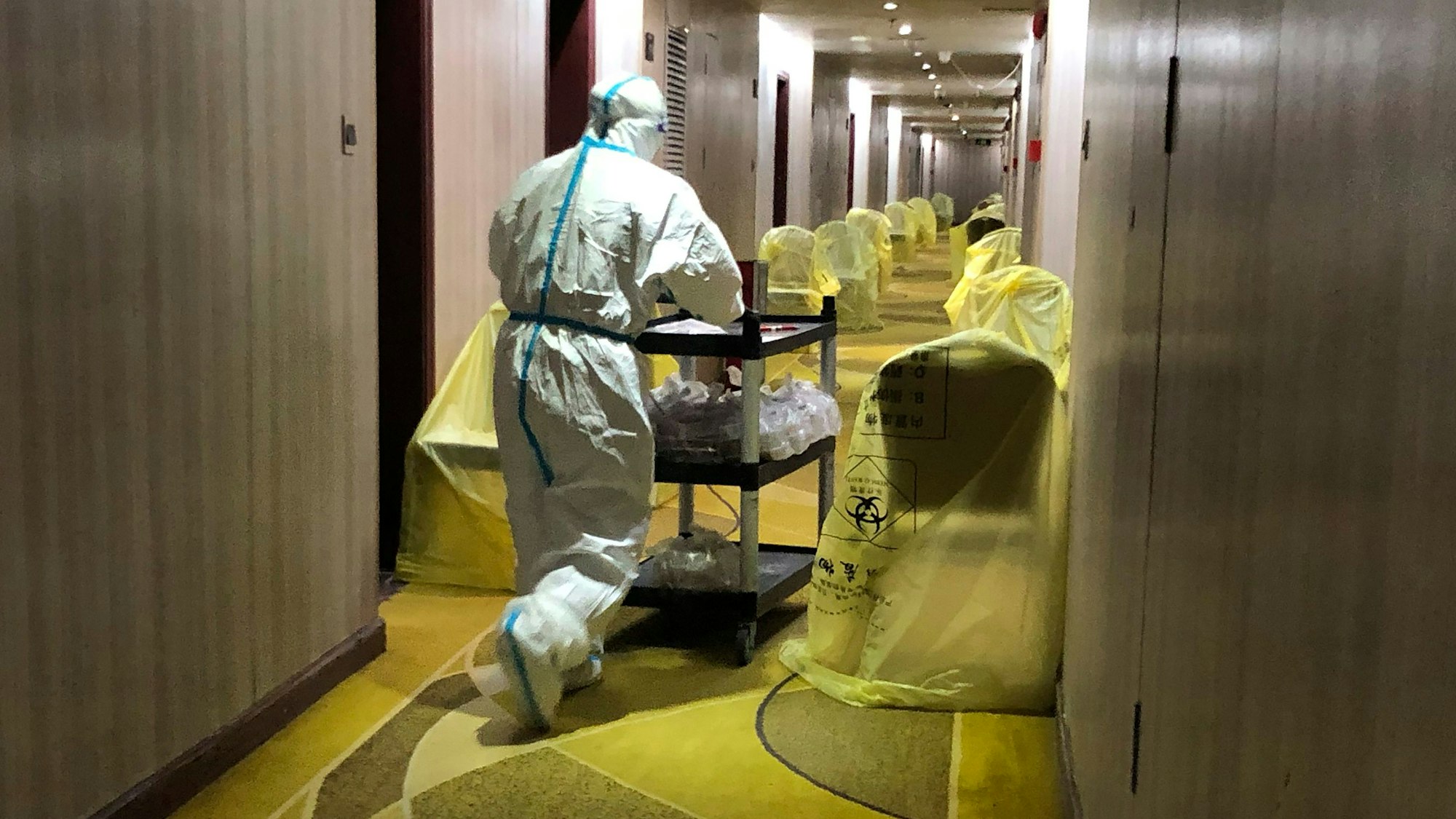 Ein Arbeiter in Schutzkleidung bringt das Frühstück in einem Quarantäne-Hotel im chinesischen Guangdong für ankommende Reisende.