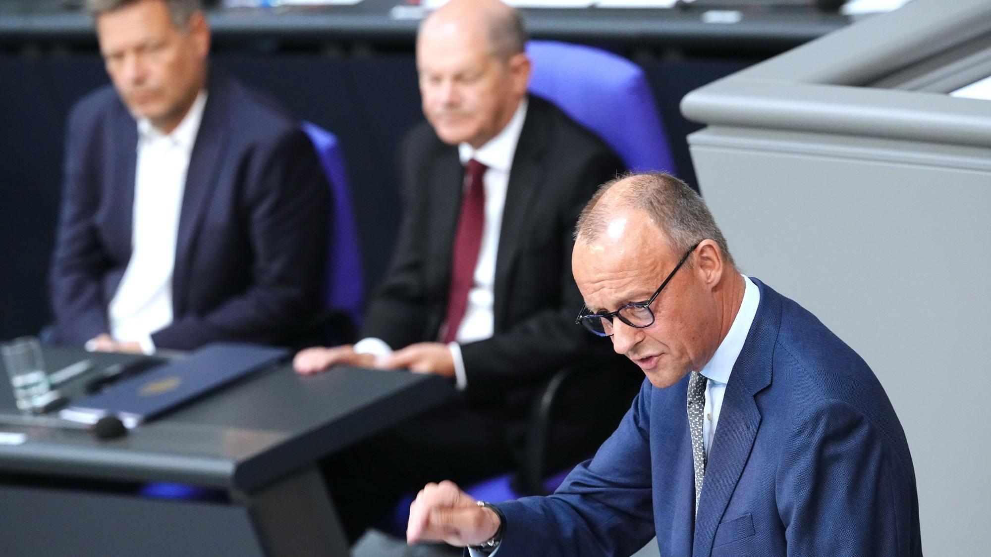 Oppositionsführer Friedrich Merz (CDU, rechts) spricht im Bundestag. im Hintergrund Kanzler Olaf Scholz (SPD, Mitte) und Vizekanzler Robert Habeck (Grüne).