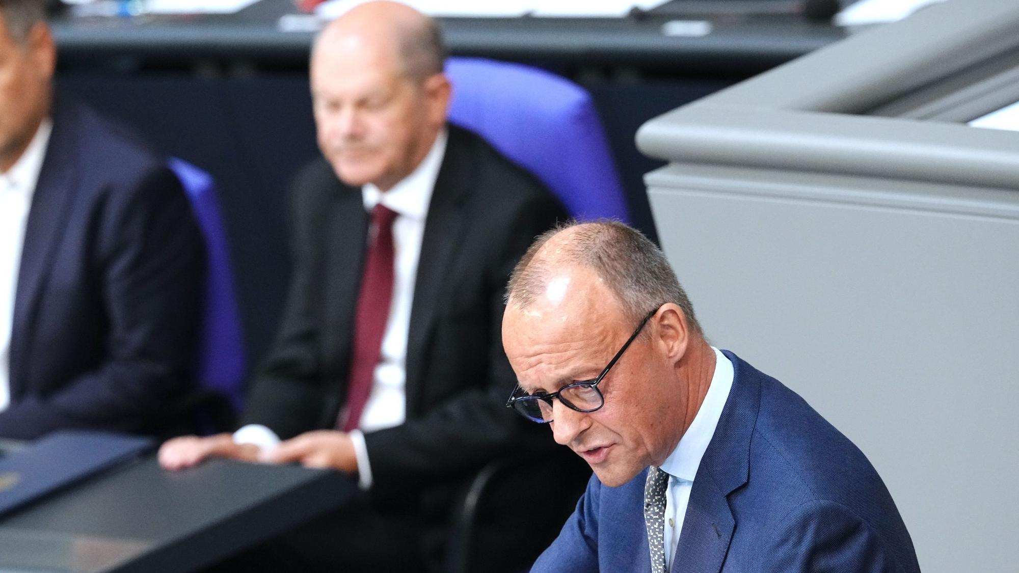 Friedrich Merz, CDU-Bundesvorsitzender und Unionsfraktionsvorsitzender, spricht in der Generaldebatte zum Haushalt im Bundestag vor Robert Habeck (l., Bündnis 90/Die Grünen), Bundesminister für Wirtschaft und Klimaschutz, und Bundeskanzler Olaf Scholz (M., SPD).