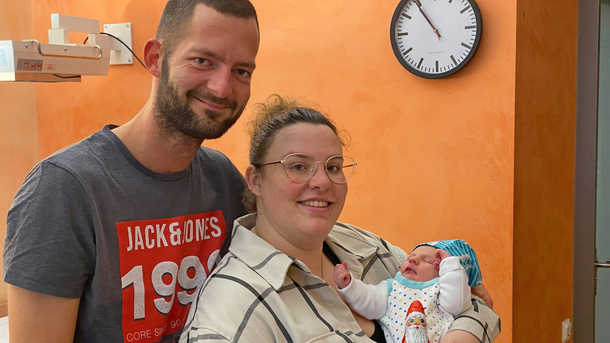 Eine Frau hält ein Neugeborenes auf dem Arm, hinter ihr steht ein Mann.