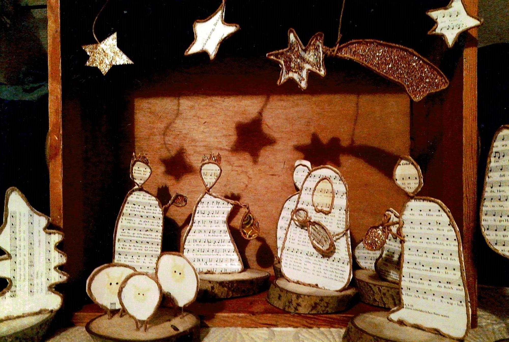 Krippenfiguren aus Notenpapier stehen auf Holzscheiben.
