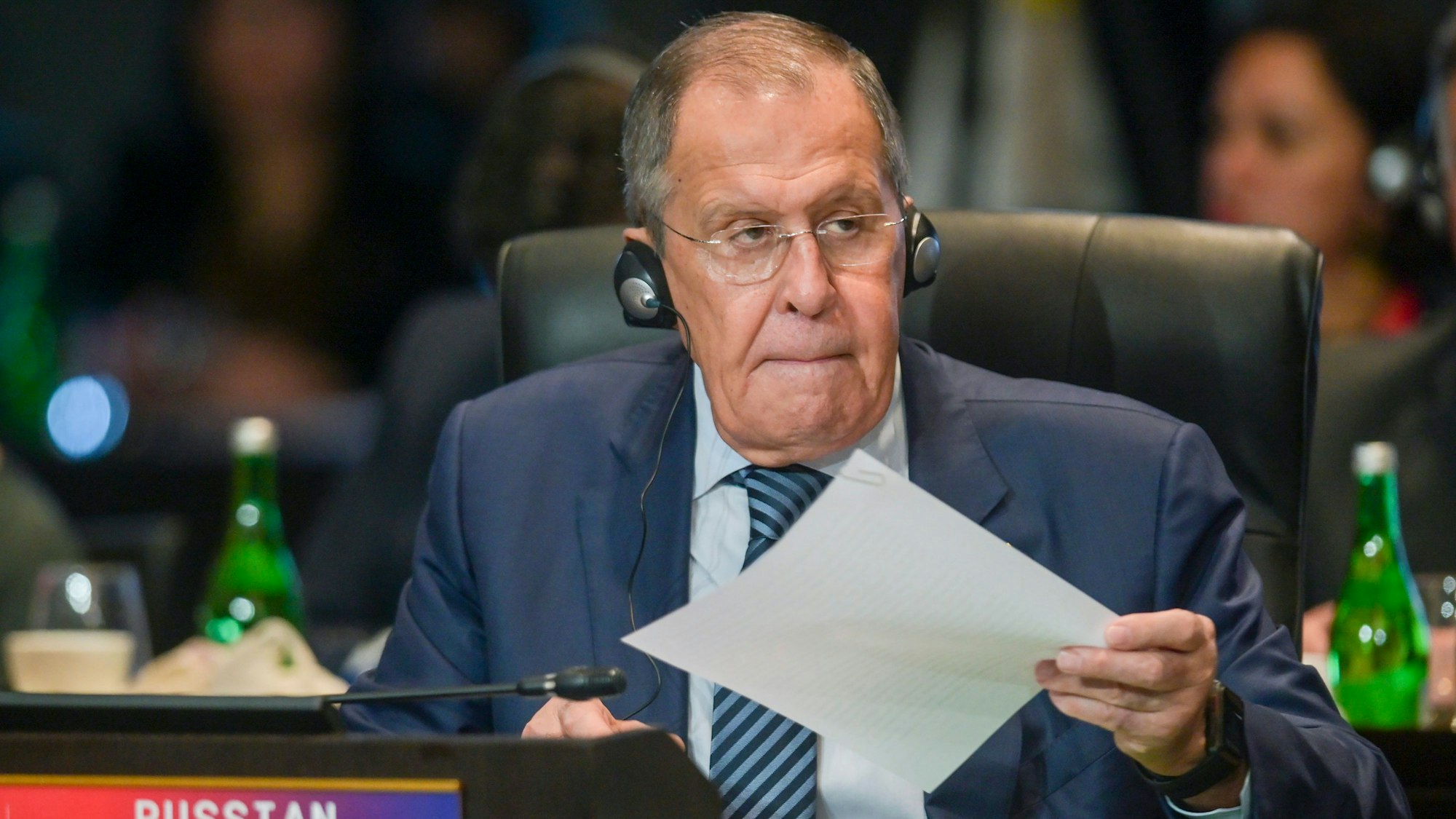 Russlands Außenminister Sergej Lawrow nimmt an einer Konferenz teil, er sitzt im Anzug auf einem Stuhl und hält ein Blatt Papier.