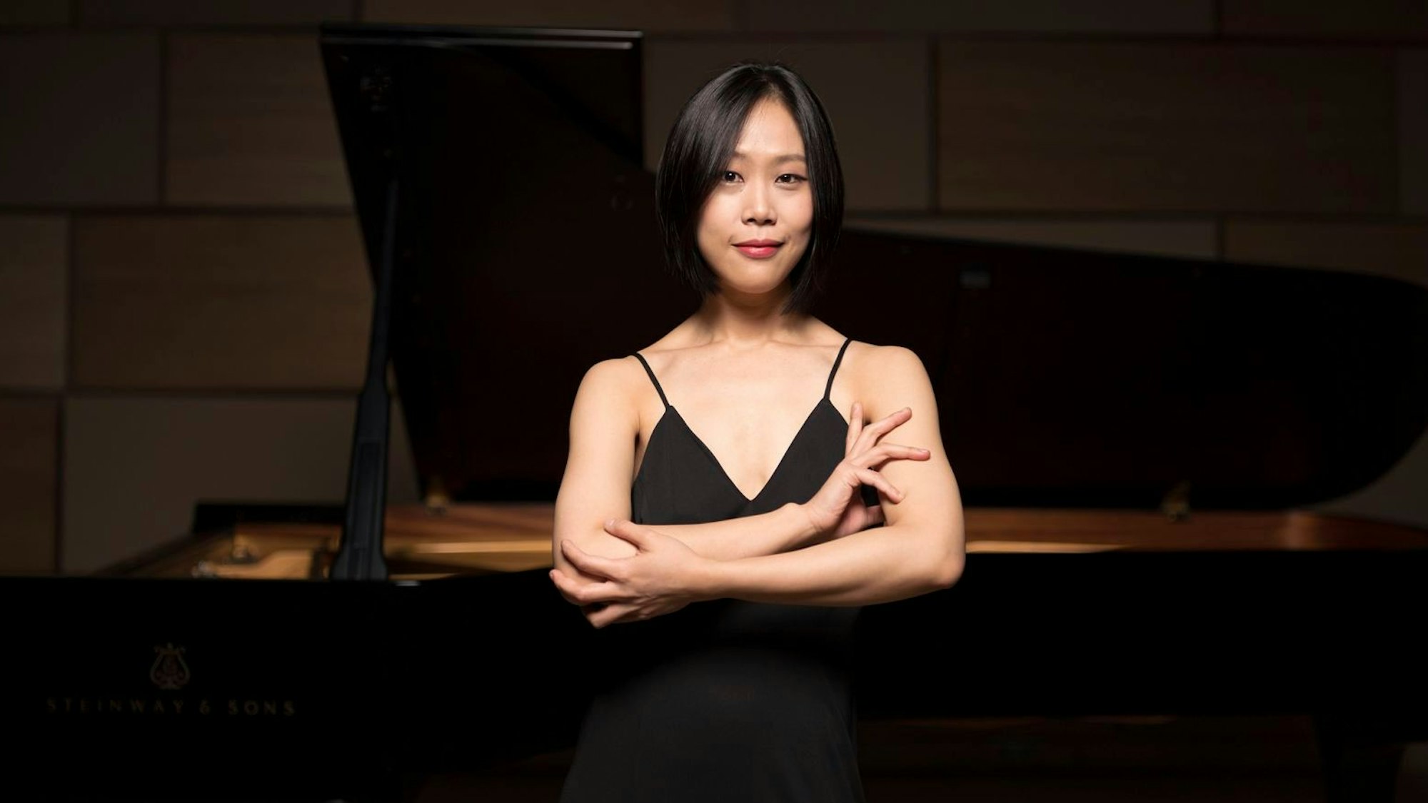 Yeol Eum Son steht mit gekreuzten Armen vor ihrem Piano