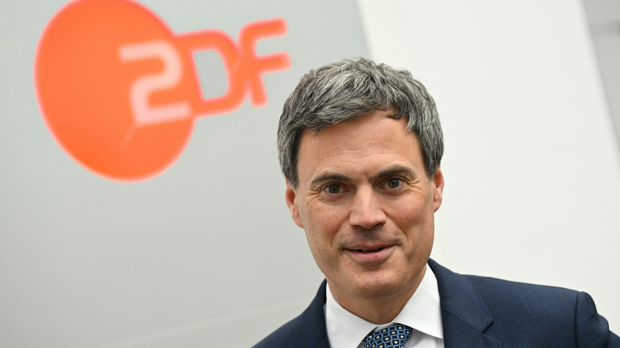 Es ist Norbert Himmler im Vordergrund zu sehen. Im Hintergrund sieht man das Logo des ZDF.
