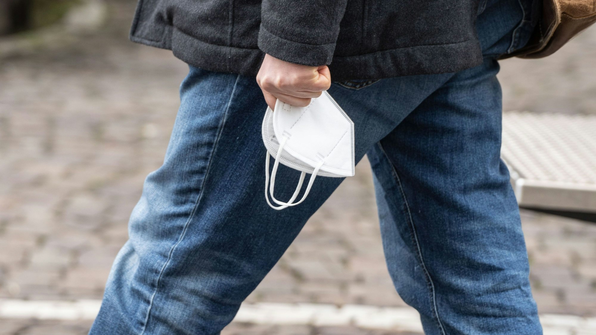Ein Passant trägt seine FFP-2-Maske in der Hand. (Symbolbild)