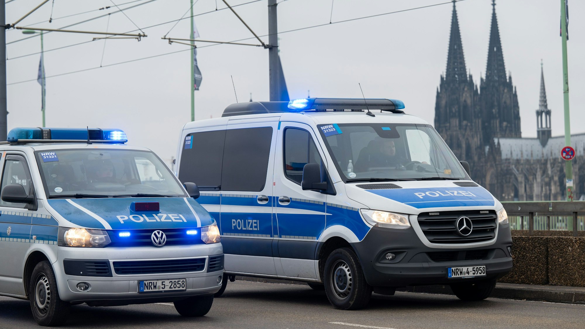 Zwei Fahrzeuge der Polizei fahren auf der Deutzer Brücke. Im Hintergrund sieht man den Dom.