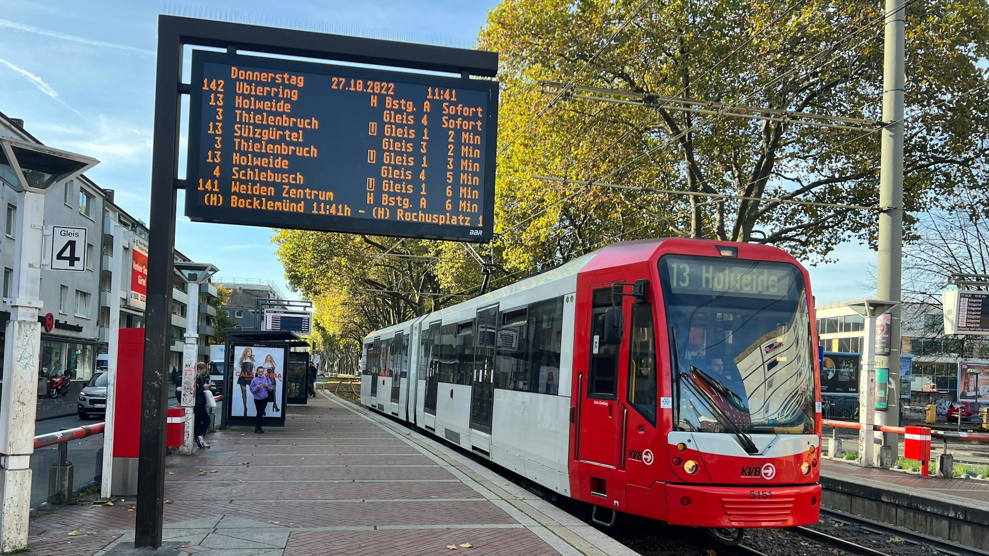 Anzeigetafel der KVB mit Bahnsteig und einem Wagen der Linie 13.