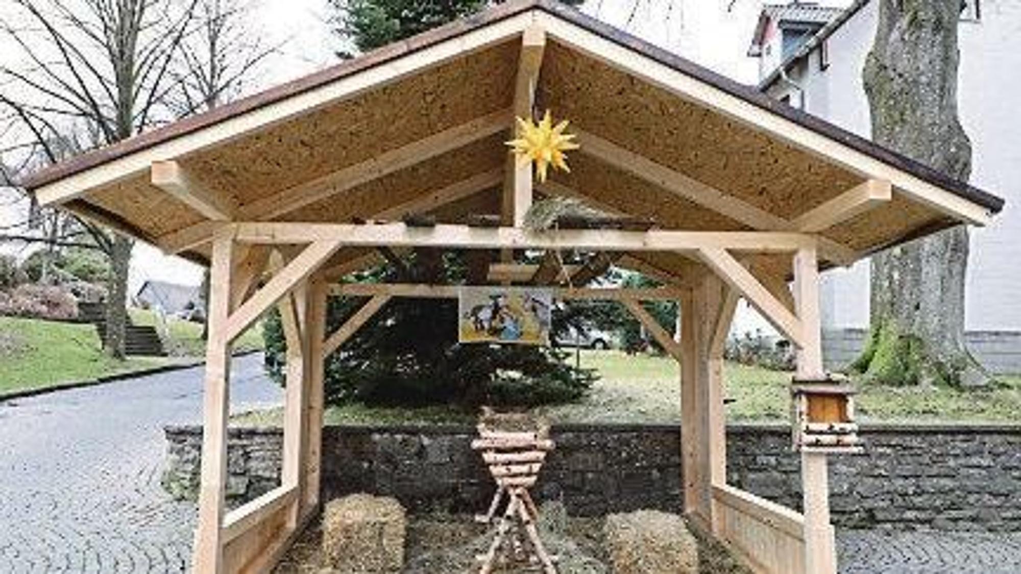 Eine Holzhütte überdacht eine Holzwiege und Stroh.