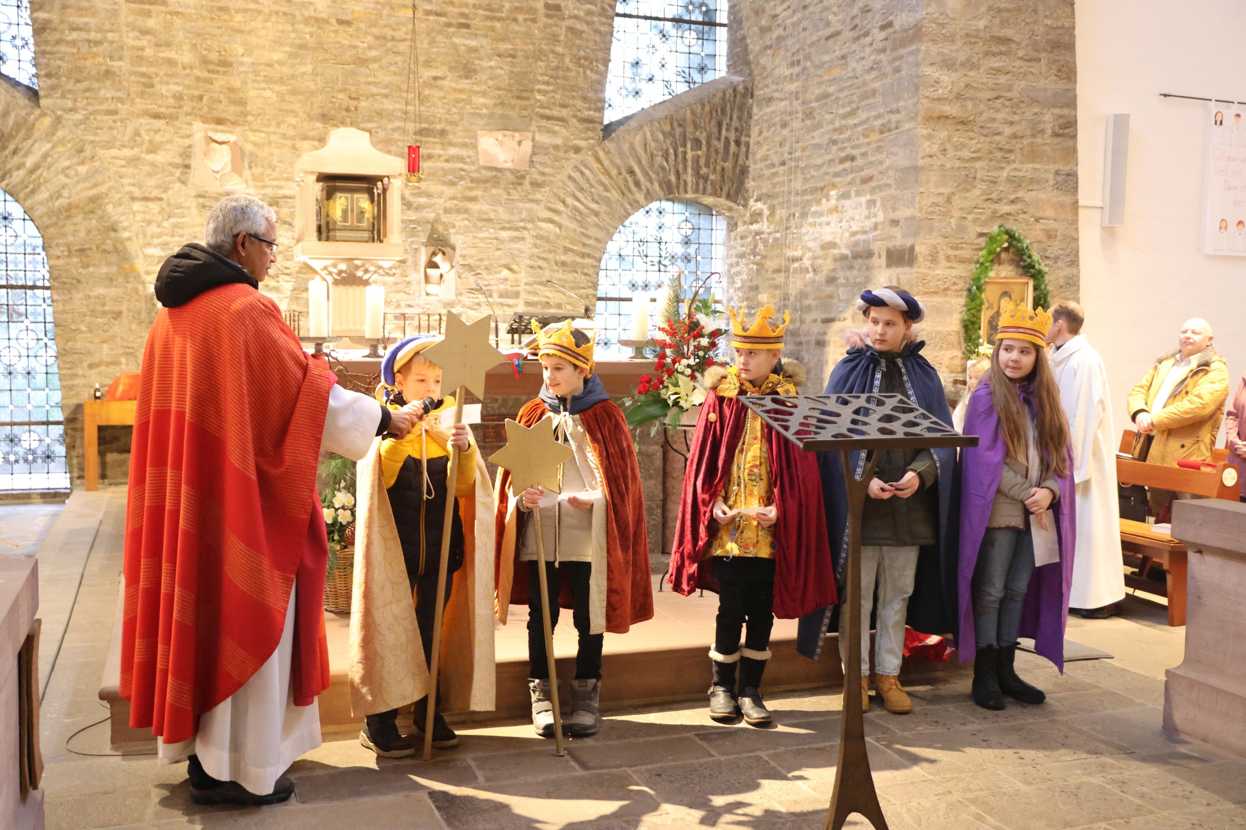 Einige Sternsinger und der Pater in der Kirche