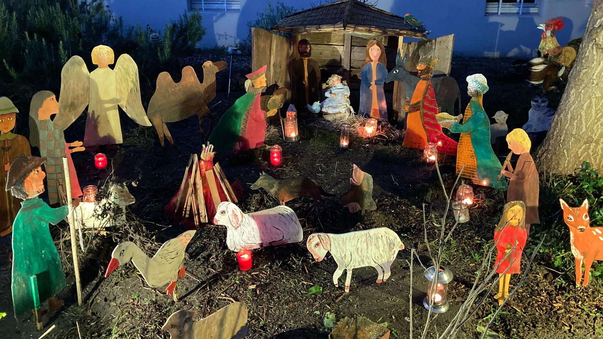 Selbstgestaltete Krippenfiguren stehen in einem Vorgarten.
