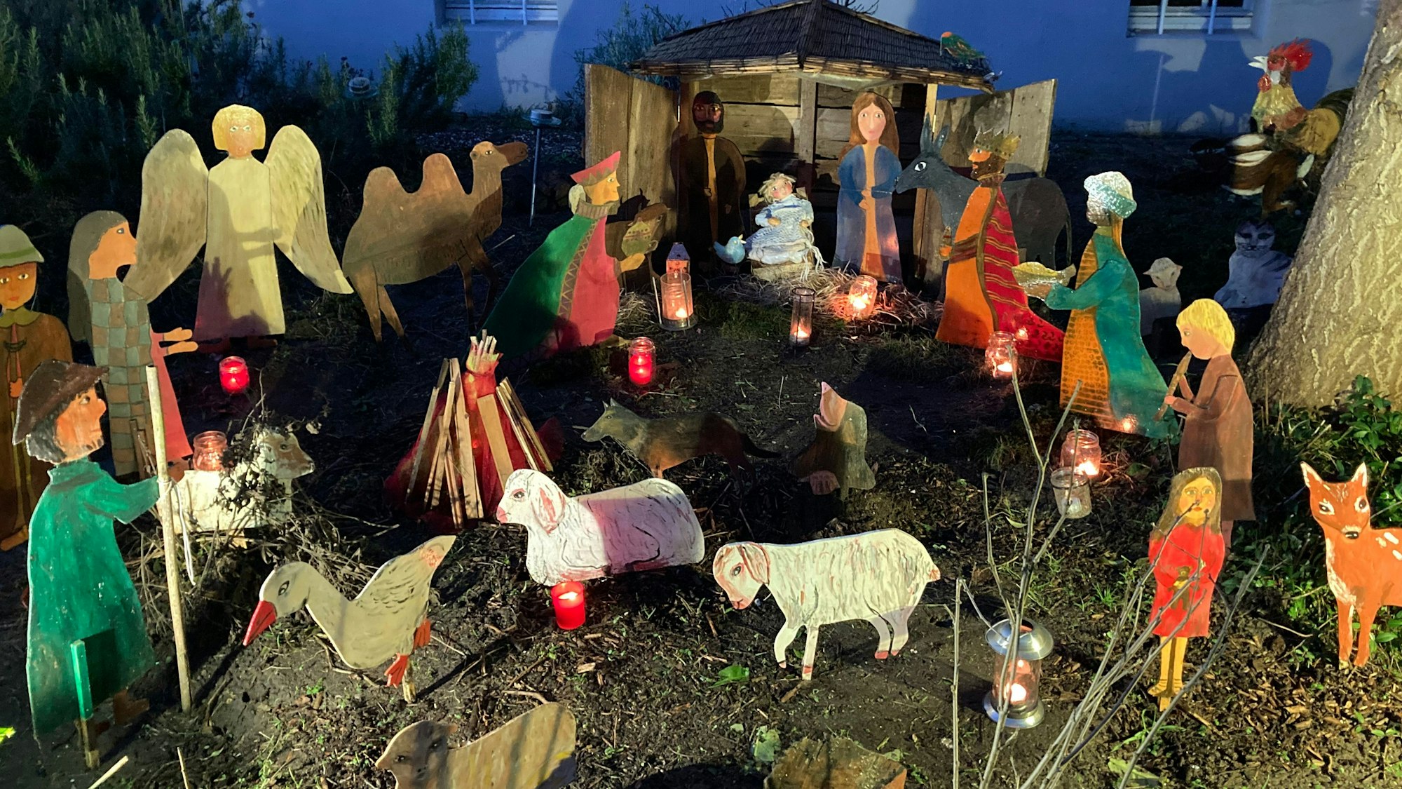 Selbstgestaltete Krippenfiguren stehen in einem Vorgarten.