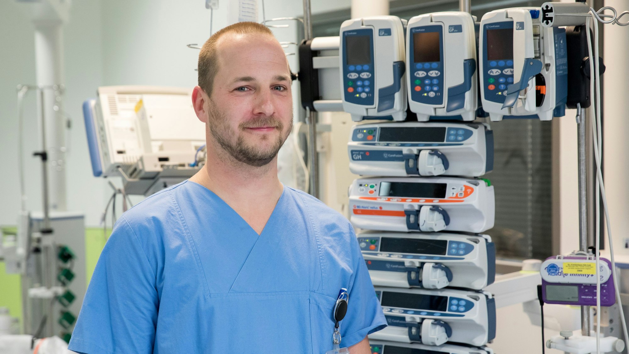 Im Bild zu sehen ist Markus Redmann in blauer Dienstkluft auf der Intensivstation des Krankenhauses.