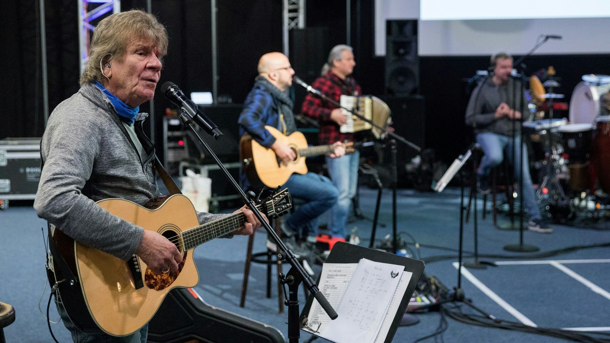 Lückerath spielt Gitarre und singt bei der Probe, im Hintergrund die anderen Bläck Fööss-Musiker.