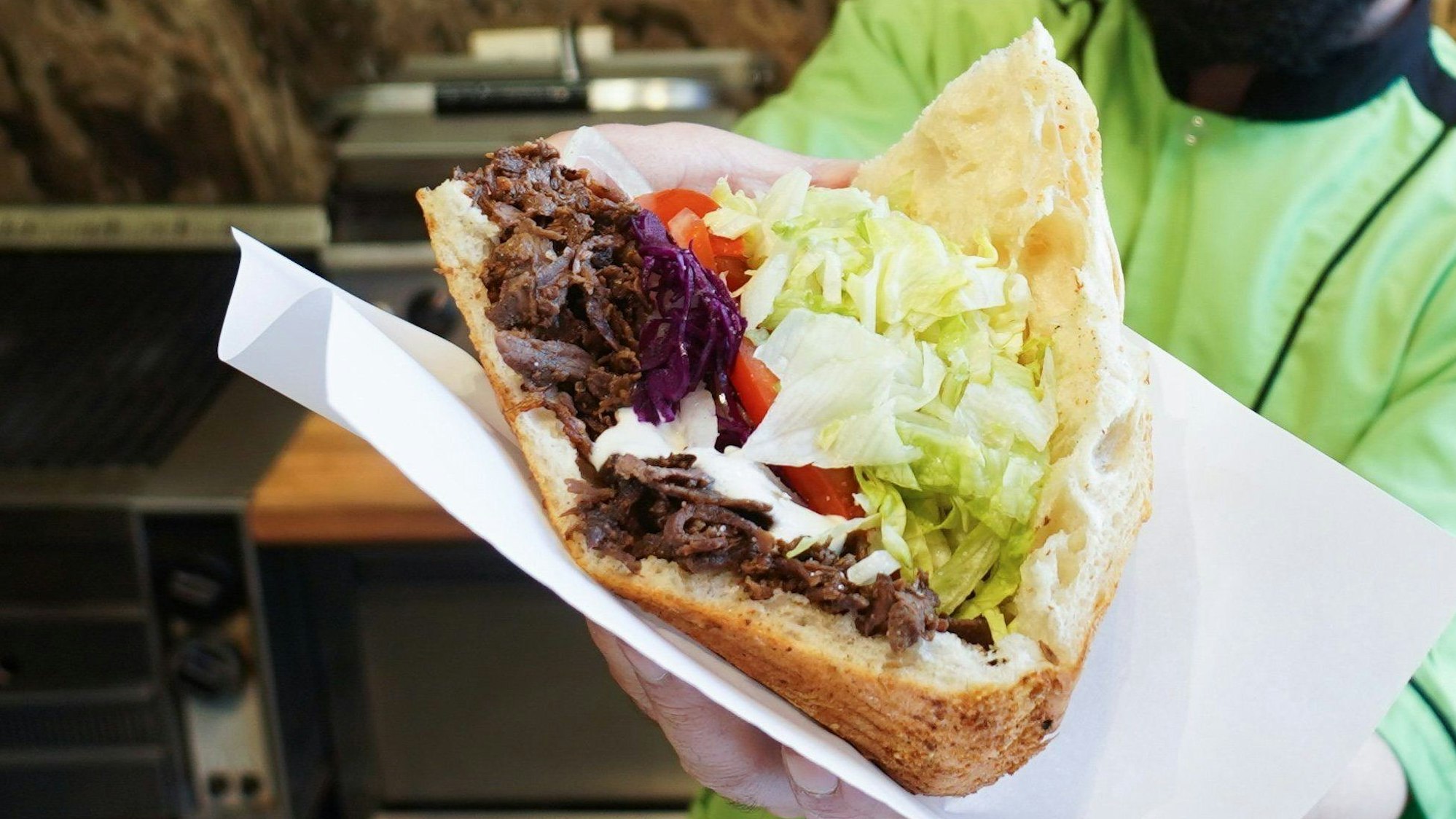 Ein Mann hält einen Döner in seinen Händen