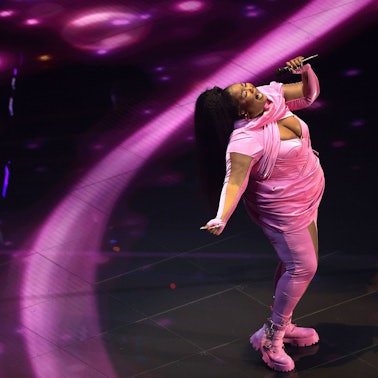 Lizzo steht im rosa Kostüm auf einer Bühne und singt.