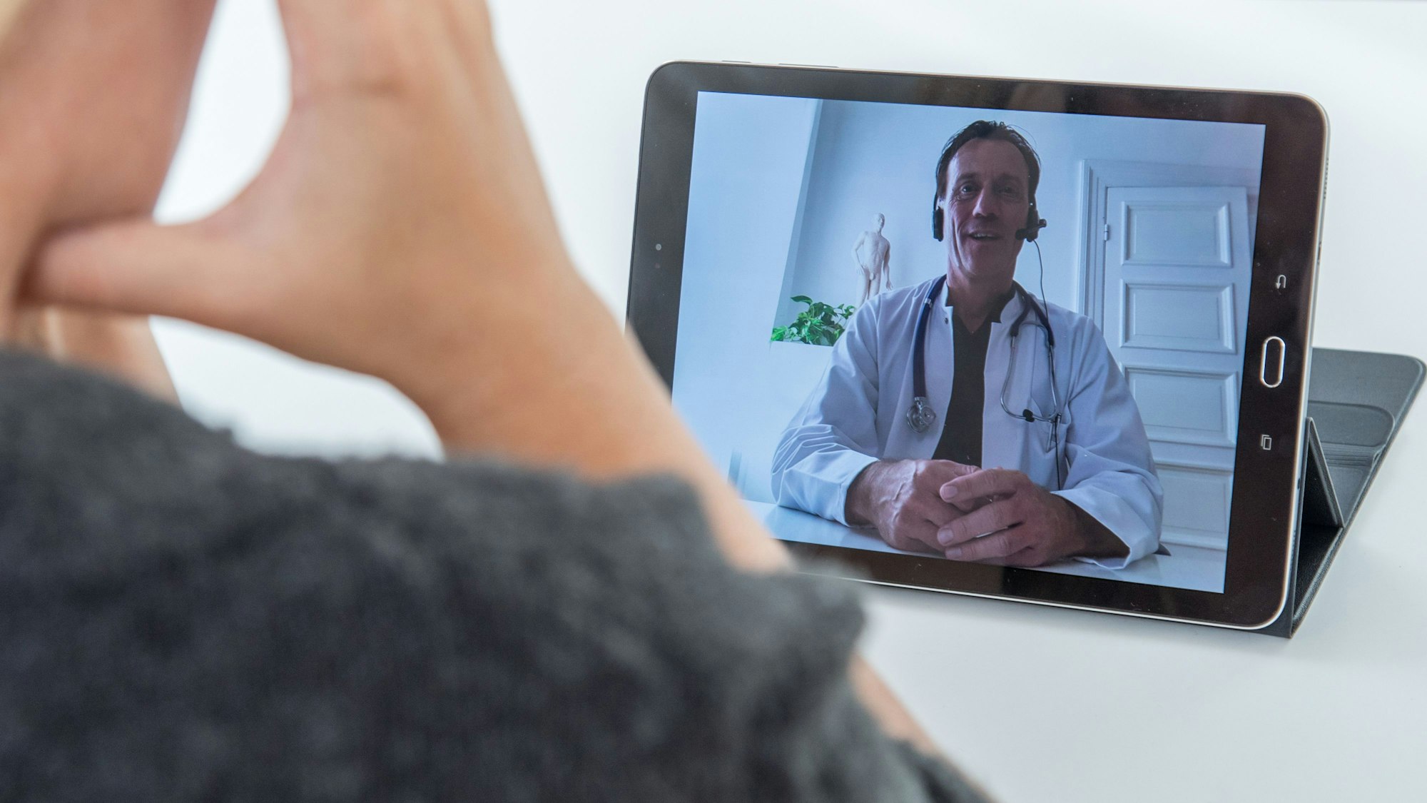 Ein Arzt, hier im Februar 2021 in Hamburg, ist per Videosprechstunde auf einem Tablet zu sehen. Die erste Video-Sprechstunde von Kinderärztinnen und Kinderärzten im Oberbergischen Kreis war laut Kassenärztlicher Vereinigung ein Erfolg.