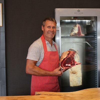 Blick auf einen Mann, der ein großes Stück Steak in den Händen hält.