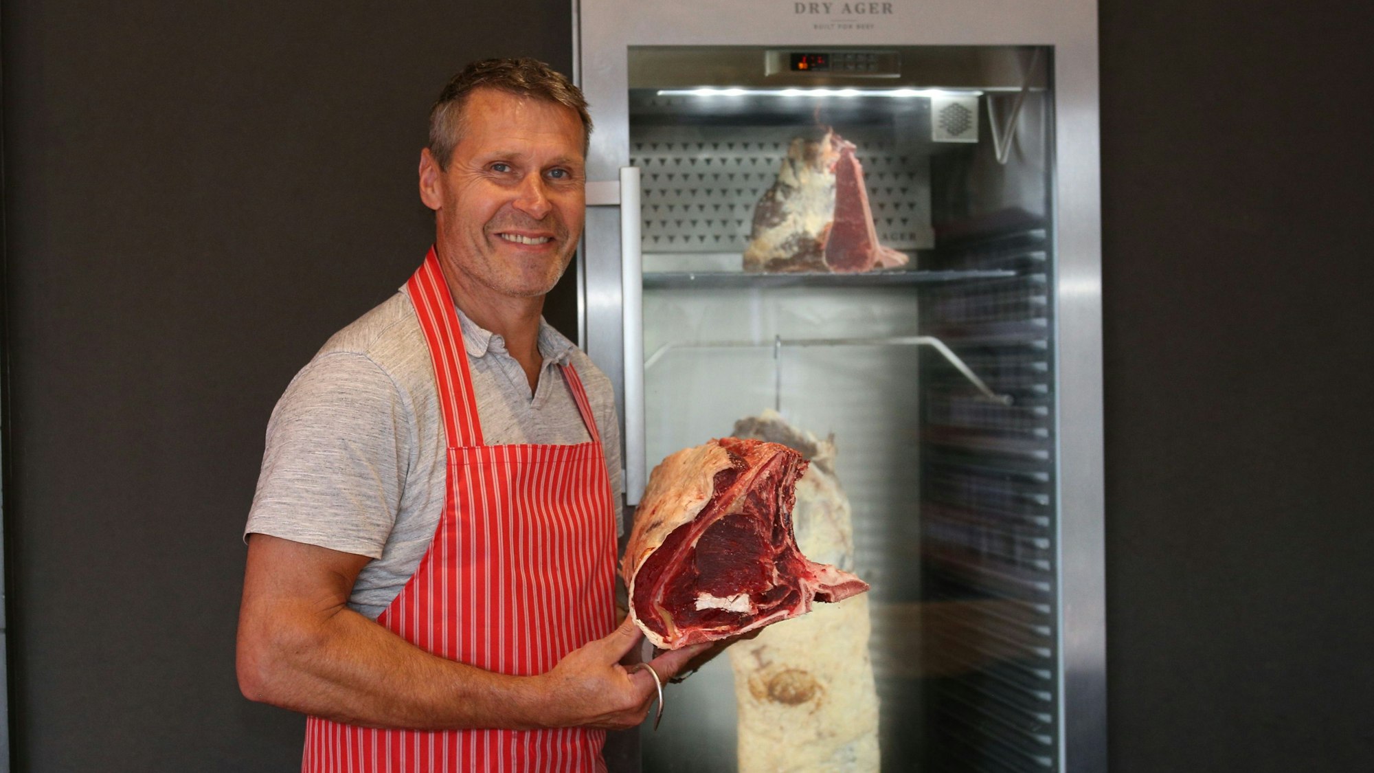 Blick auf einen Mann, der ein großes Stück Steak in den Händen hält.