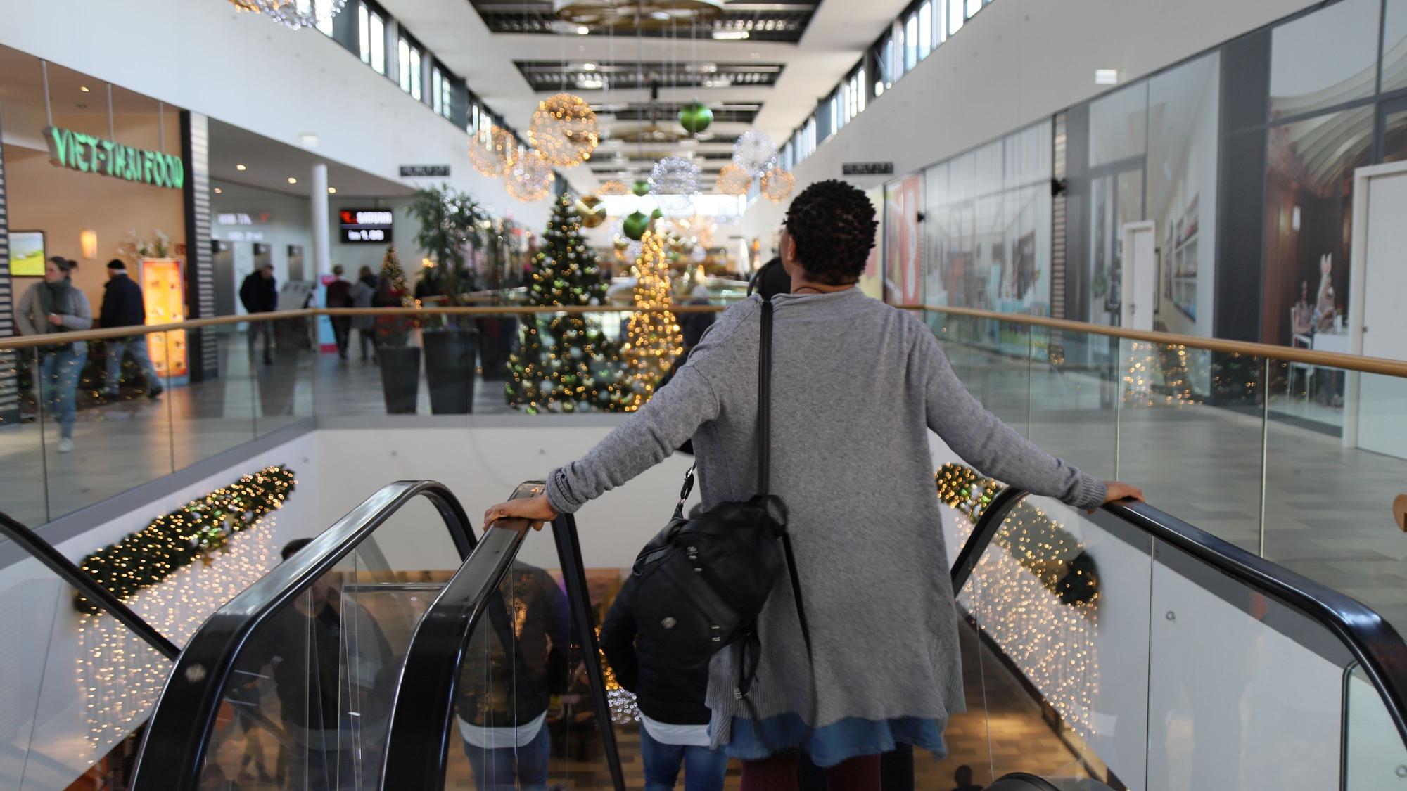 Eine Frau in der Sankt Augustiner Shopping-Welt steht im Dezember 2022 auf einer Rolltreppe.