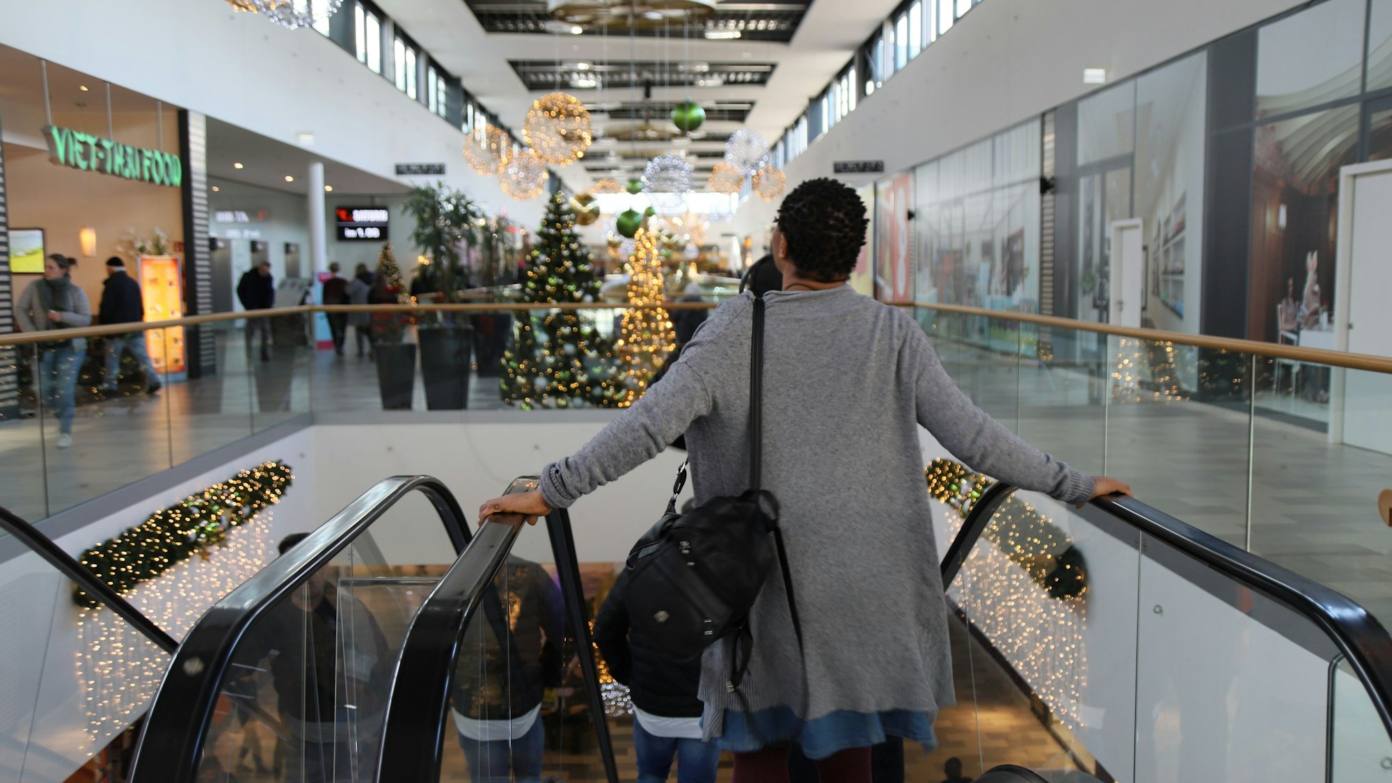 Eine Frau in der Sankt Augustiner Shopping-Welt steht im Dezember 2022 auf einer Rolltreppe.