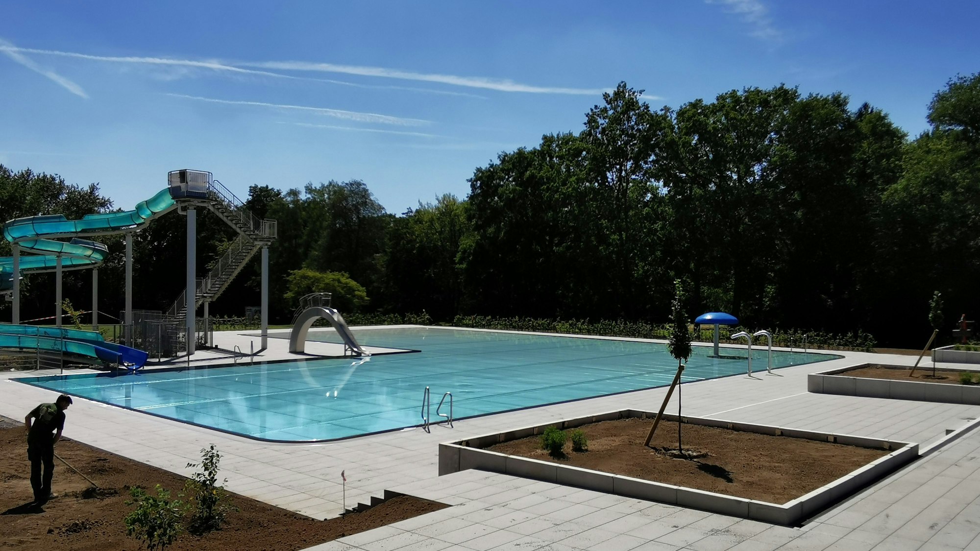 Der Außenbereich des Kombibades mit Rutsche und Beeten.