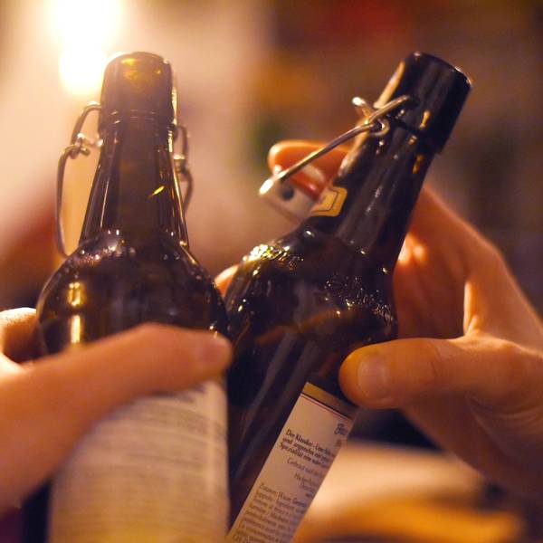 Zwei Menschen stoßen mit Bier in der Flasche an.
