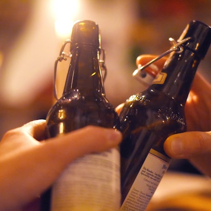 Zwei Menschen stoßen mit Bierflaschen an