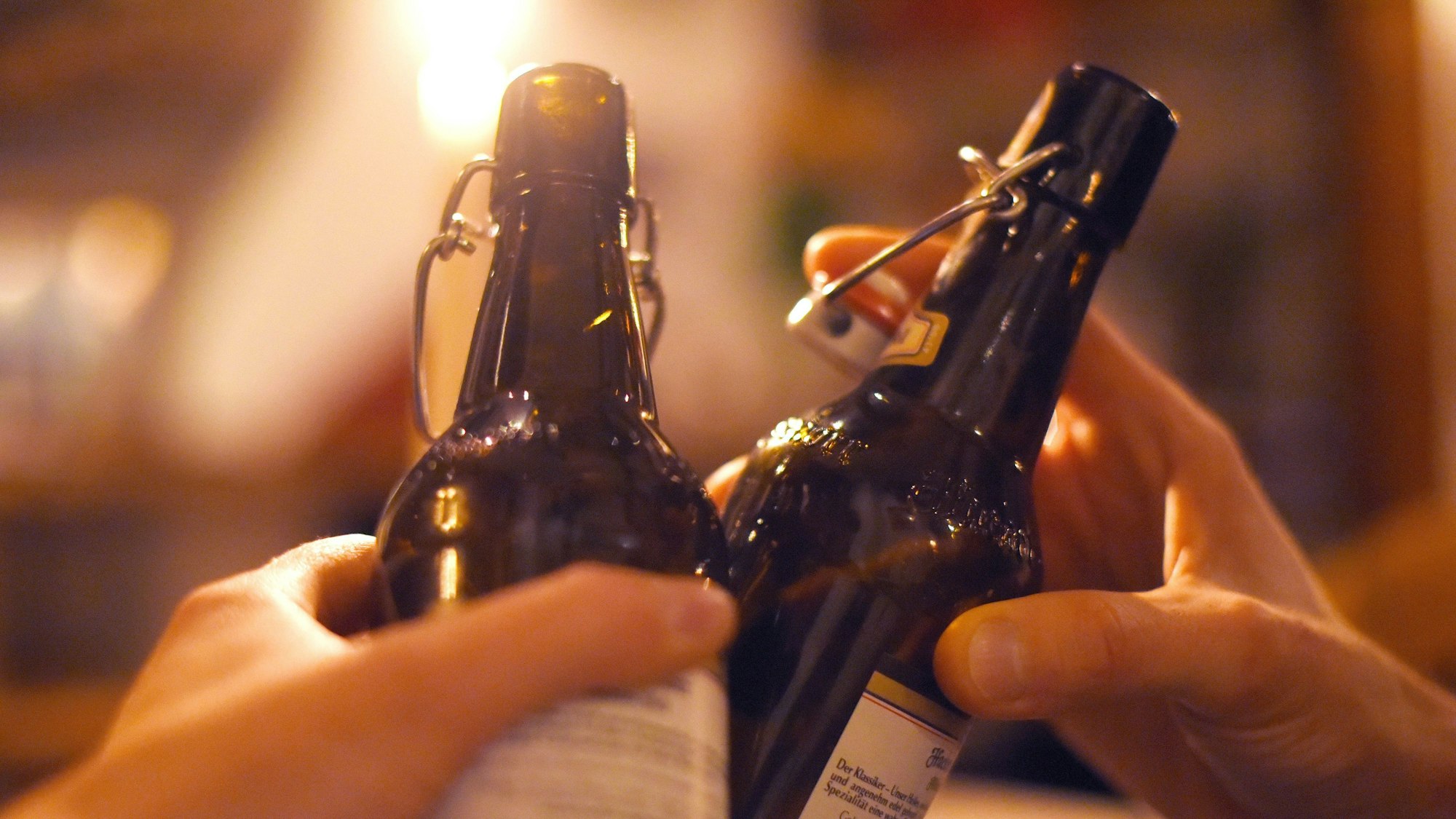Zwei Menschen stoßen mit Bierflaschen an