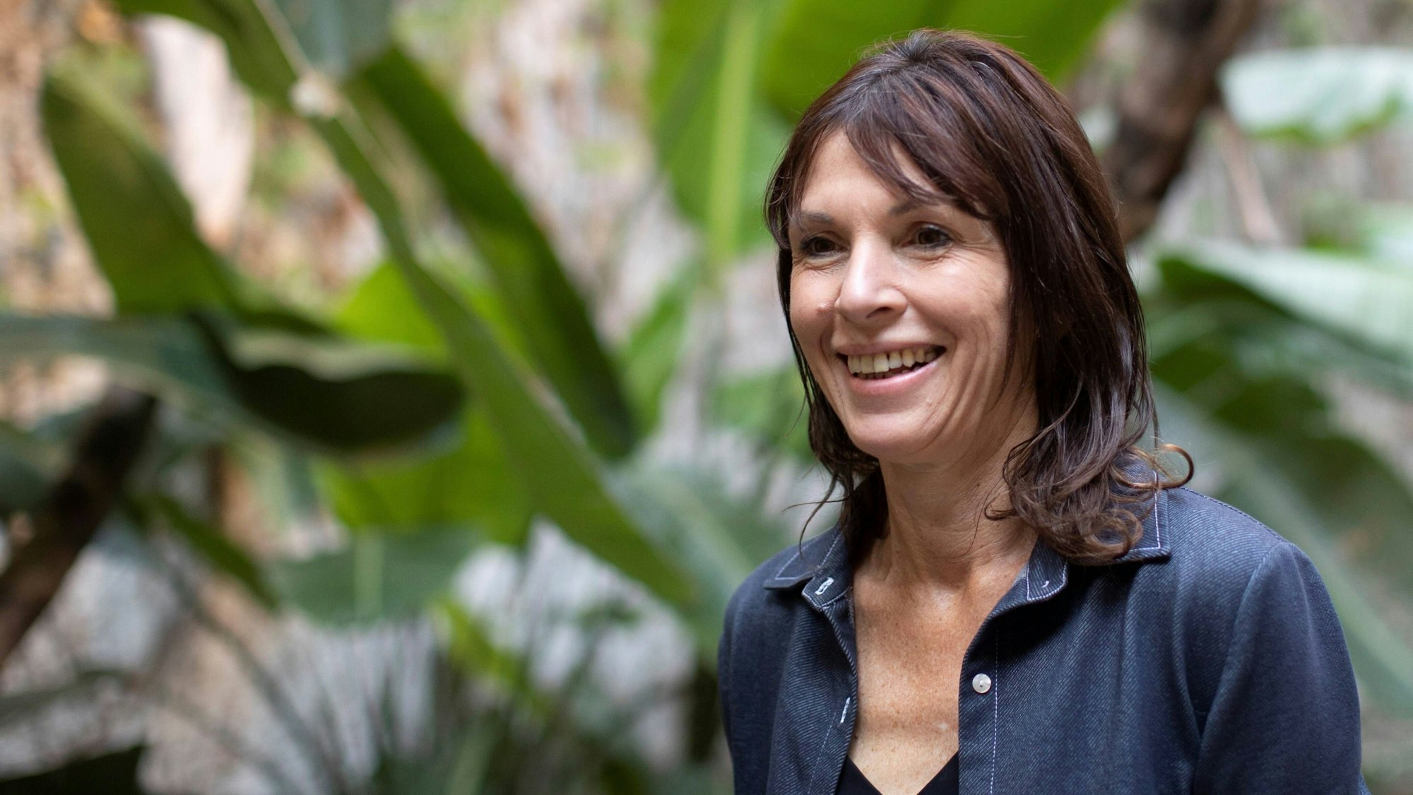 Die kanadische Autorin Rachel Cusk steht vor einem grünen Pflanzengarten.