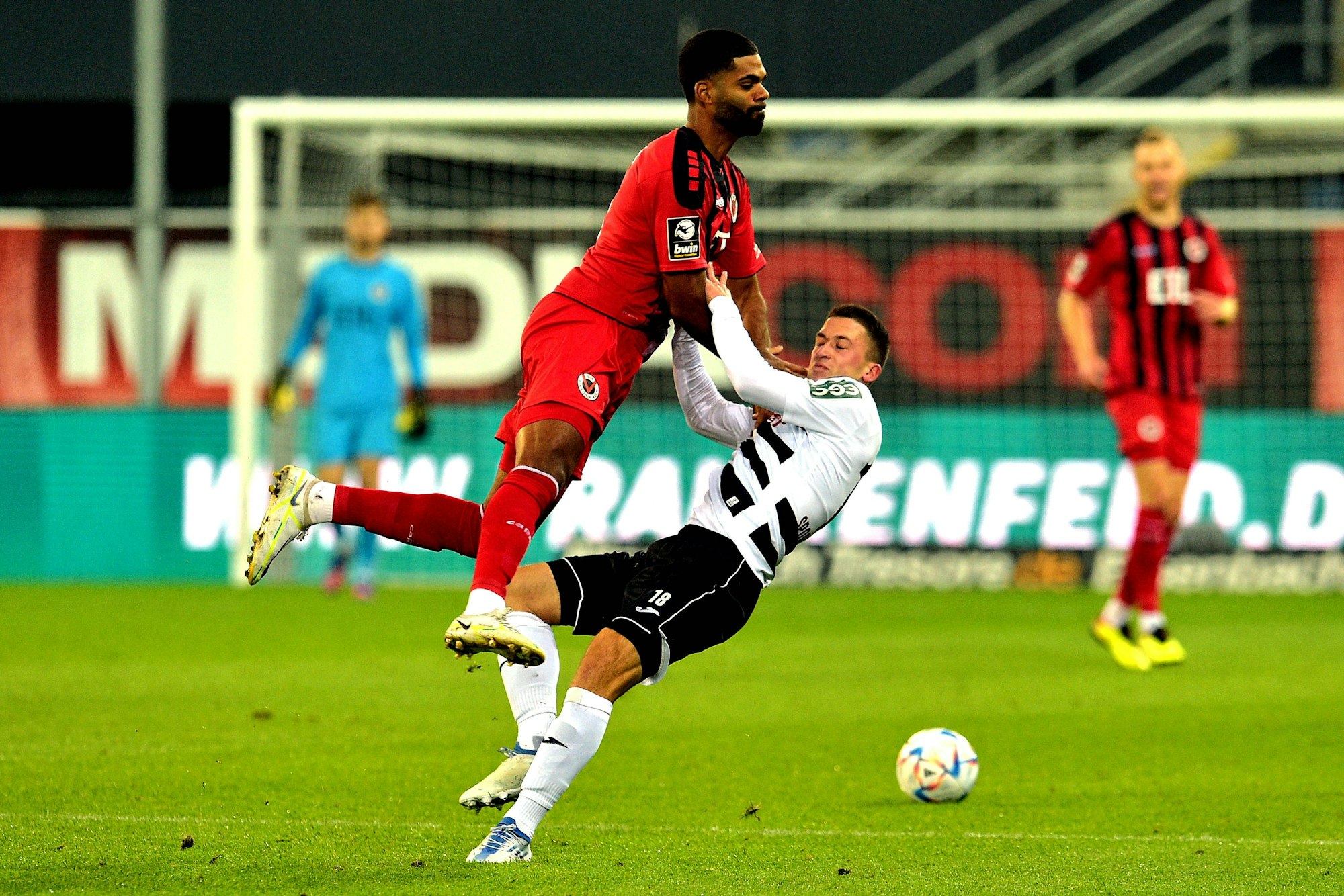 Ein Fußballspieler stößt im Zweikampf mit seinem Gegner zusammen.