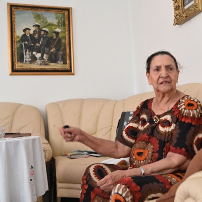 Philomena Franz sitzt auf ihrem Sofa und gestikuliert.