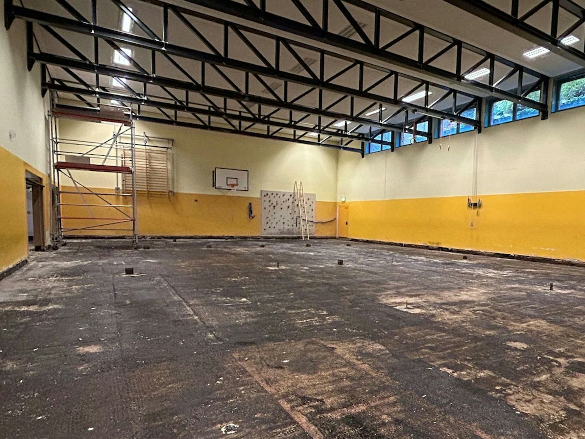Die Turnhalle an der KGS Kupfergasse kann seit drei Jahren nicht genutzt werden. Der Boden wurde herausgerissen und ist schwarz. Bis auf ein Gerüst und einen Basketballkorb ist die Halle leer.