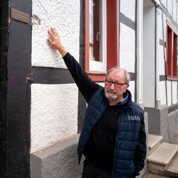 Robert Zimmermann zeigt an seinem Haus in Arloff, wie hoch das Wasser während der Flut 2021 stand. Dort ist auch eine Plakette angebracht worden, die das historische Hochwasser dokumentiert.