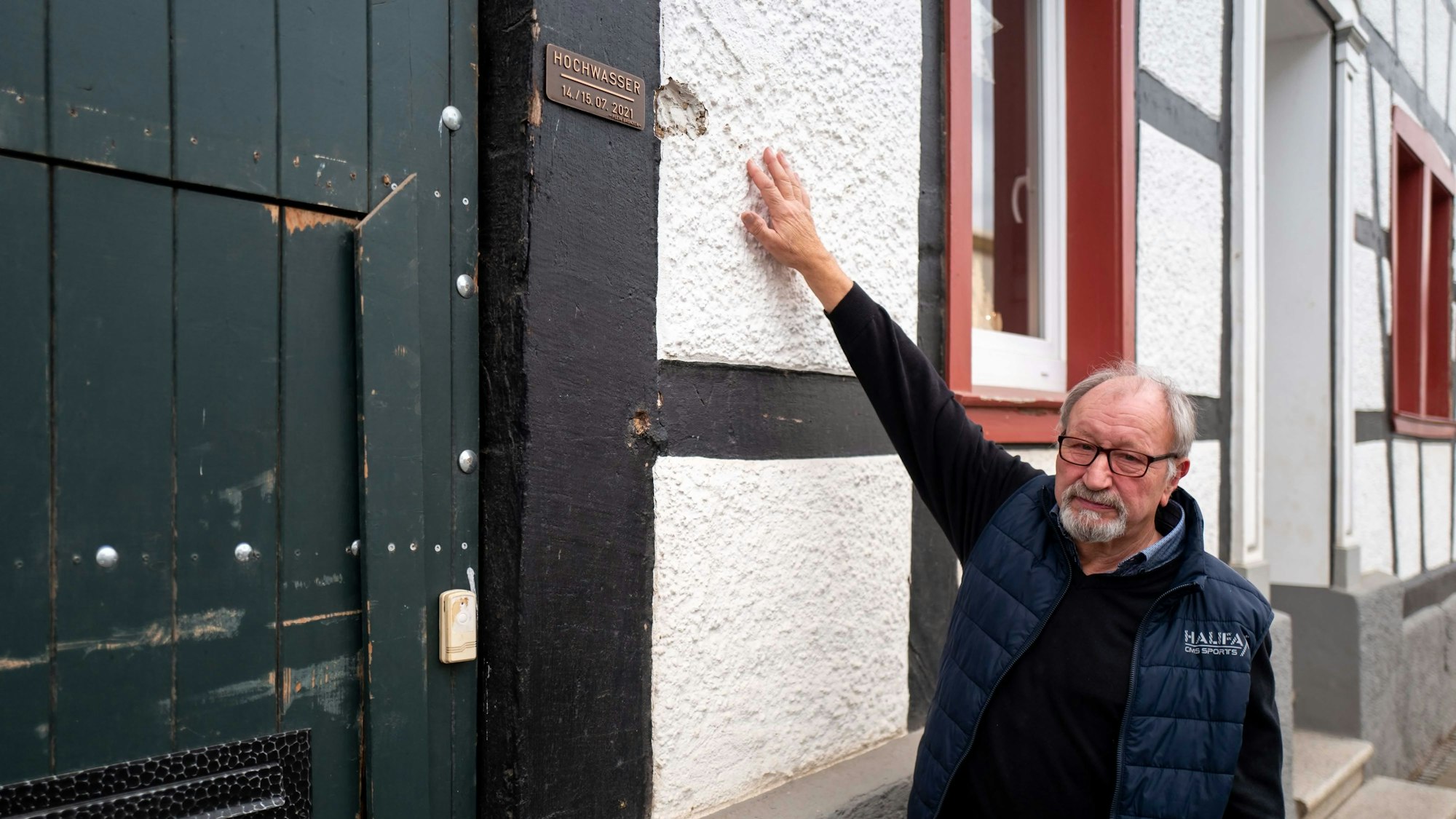 Robert Zimmermann zeigt an seinem Haus in Arloff, wie hoch das Wasser während der Flut 2021 stand. Dort ist auch eine Plakette angebracht worden, die das historische Hochwasser dokumentiert.