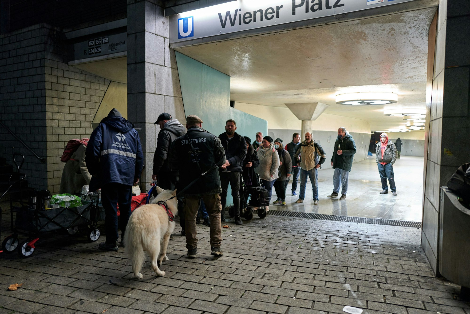 Obdachlose Menschen stehen am Wiener Platz in der Schlange für die Essensausgabe.
