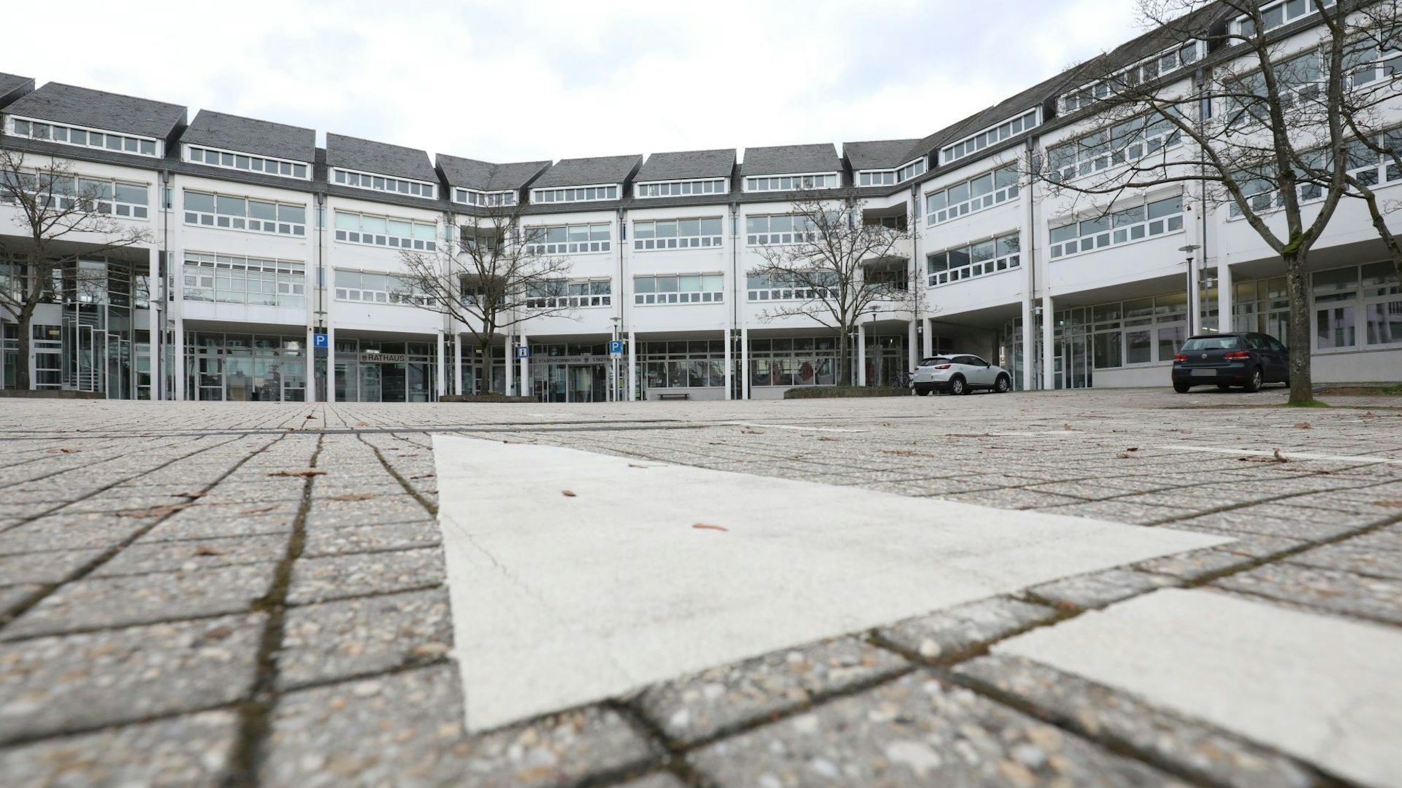 Das Rathaus in Bad Honnef mit zwei davor geparkten Autos gegen einen bewölkten Himmel fotografiert.