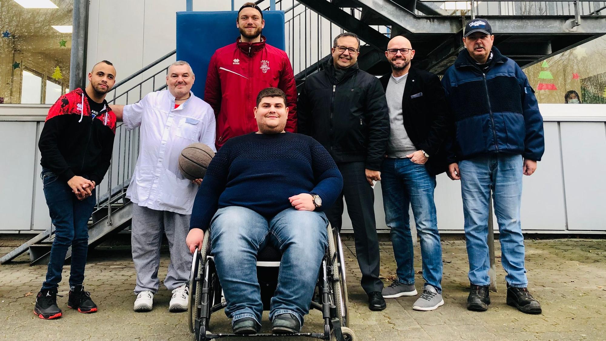 Basketballer Melvin Jostmann mit Mitarbeitenden der Werkstatt.