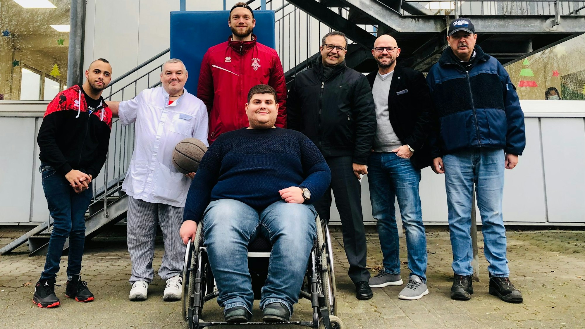 Basketballer Melvin Jostmann mit Mitarbeitenden der Werkstatt.
