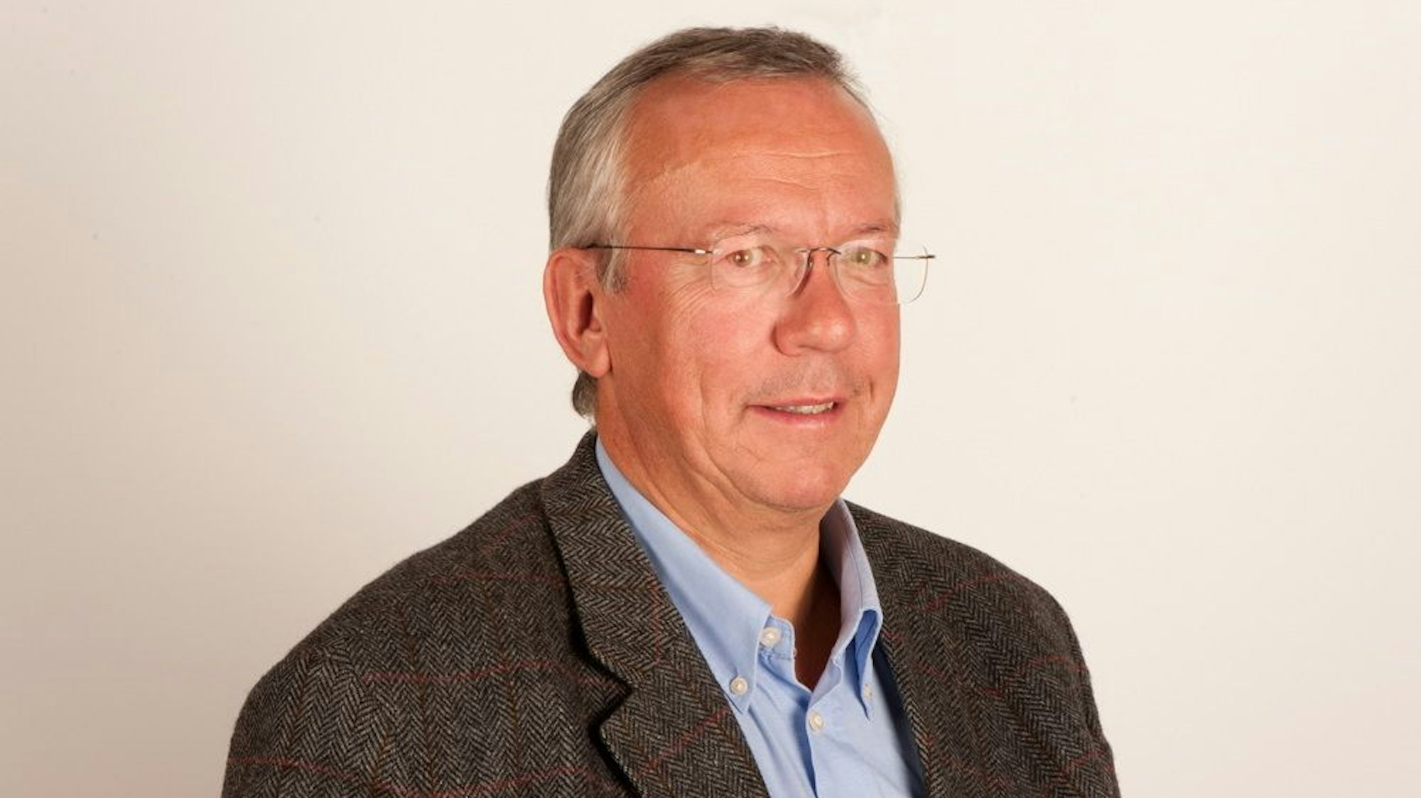 Dr. Peter Melchers in einem blauen Hemd und dunklem Anzug.